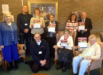 Group photo with several people including residents holding fire safety leaflets