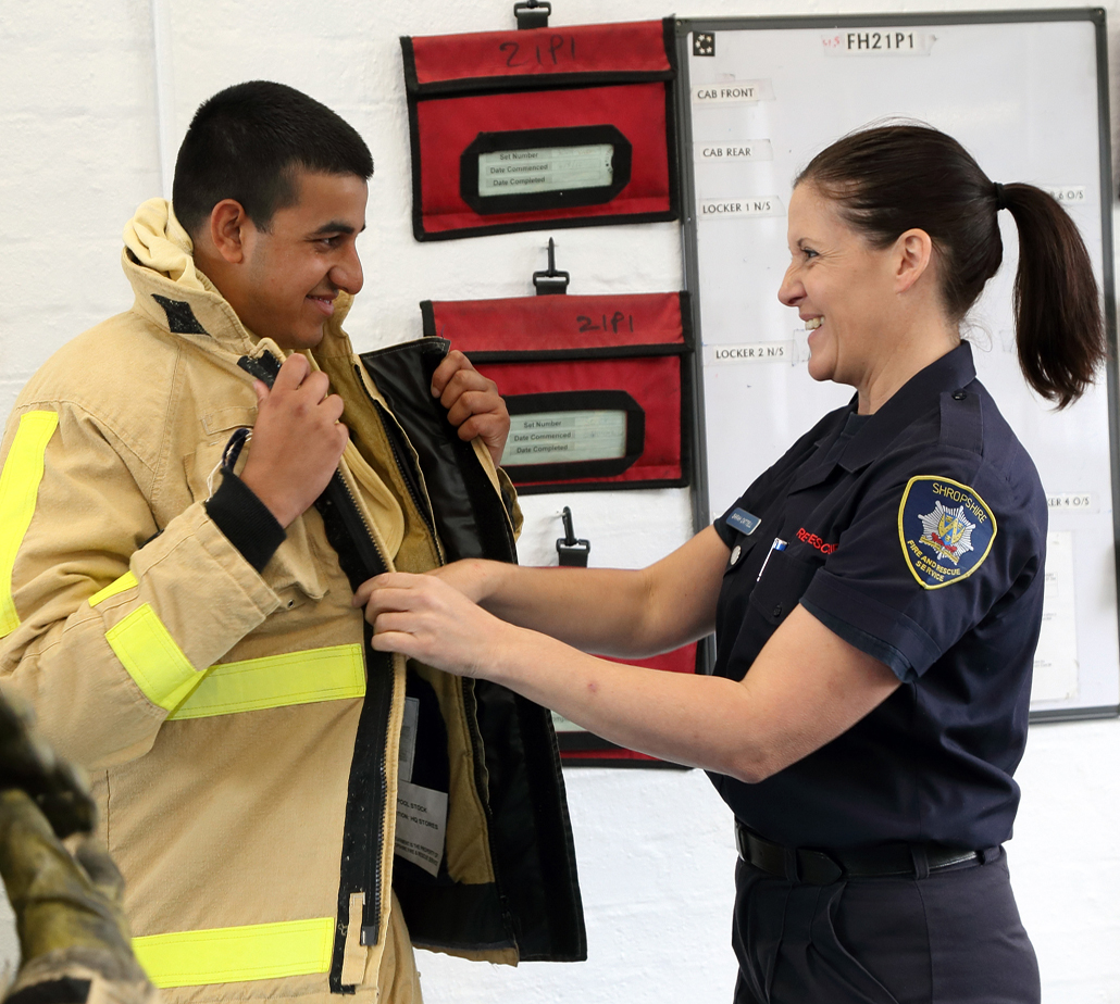 Akib Ali tries on a firefighter’s jacket for size from firefighter Sarah Cattell