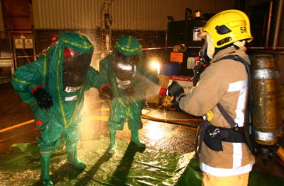 Firefighter hozes down colleagues wearing chemical suits