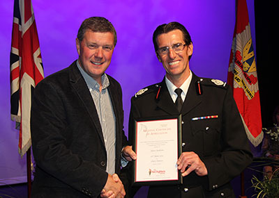 Dave shaking hands with Chris as he accepts the certificate, both smiling to camera