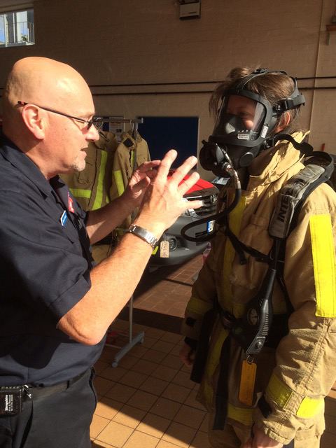 Firefighter Shaun Powell shows Becca Peace-Winn how the breathing apparatus works.
