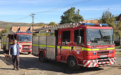 Photo of two ex SFRS fire appliances on a sunny rough road in Romania