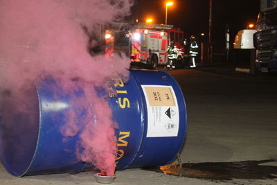 Chemical barrel on its side leaking and giving off pink smoke