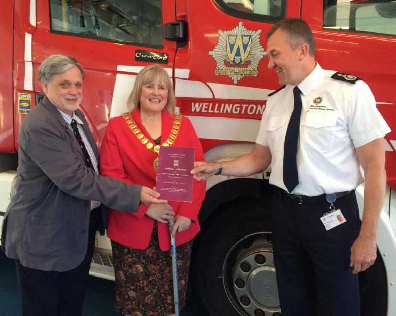 Professor Howard Davies, of the national Fire Brigade Society, with Wellington Mayor Cindy Mason-Morris, presents the original 1953 opening programme to Chief Fire Officer Rod Hammerton.