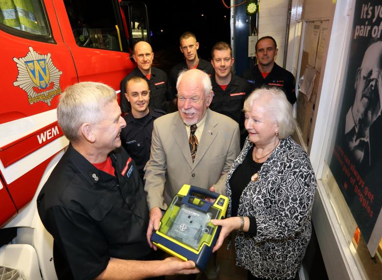 Pensioner John Luce and wife Margaret say thank you to Wem firefighters’ for saving his life. Pictured are Watch Manager Phil Smith (front) with the defibrillator used to carry out the lifesaving rescue with back row, L-R, Darren Jones, Jon Green, Gary France, Leon Turner and Vic Young.