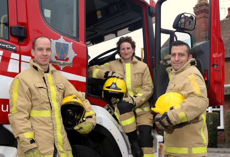 Three firefighters pose with a fire appliance
